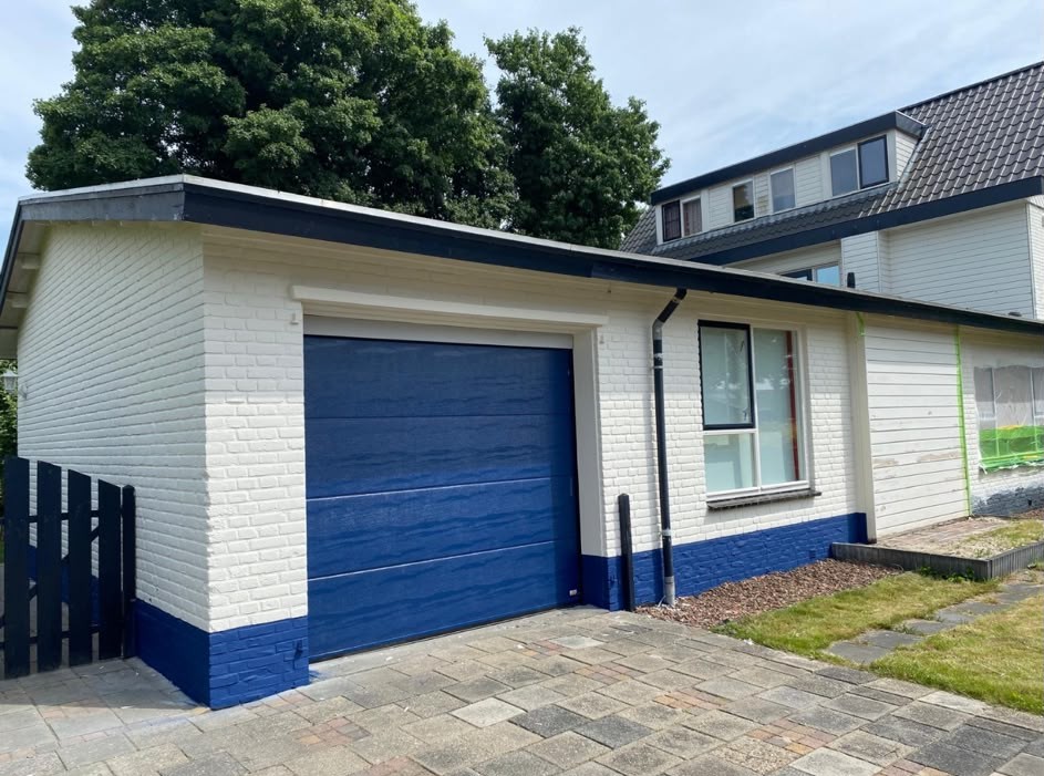 Gecoate gevel met blauwe plint en garage deur